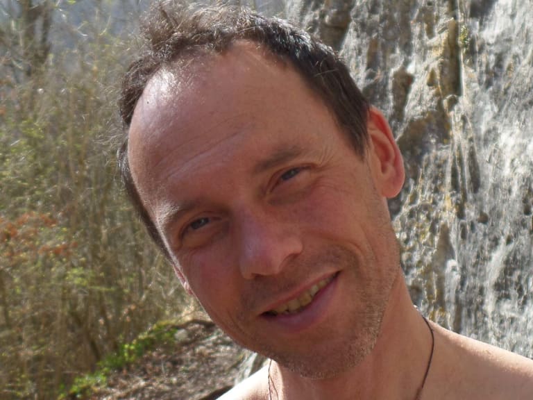 Klettertrainer Volker Wild lächelt vor einer strukturierten Felswand mit grauen und gelblichen Gesteinsfarben.