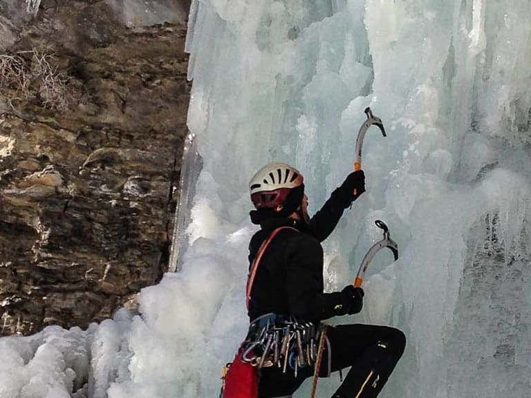 Mit zwei Eisgeräten und Steigeisen klettert Bergführer Peter Klug aktiv an einer gefrorenen Eiswand hinauf.