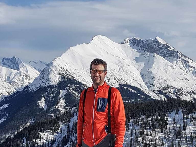 Im Tiefschnee an der Zugspitze lächelt Bergwanderführer Michael Lichtenstern in orangeroter Jacke in die Kamera.