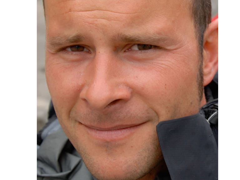 Bergführer Uwe Berg lächelt in die Kamera und trägt dunkle technische Outdoor-Jacke bei Tageslicht.
