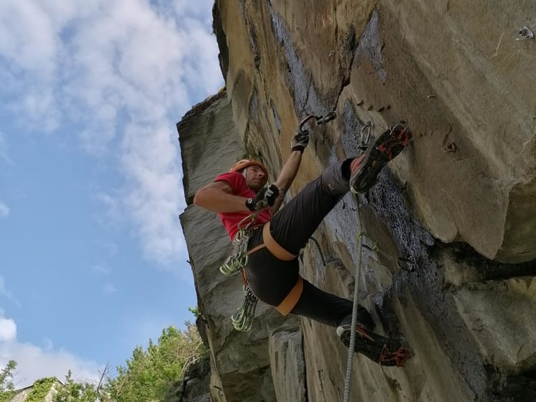 An einer steilen Kalksteinwand klettert Bergführer Rolando Varesco im roten Shirt, während eine zweite Person im Hintergrund folgt.