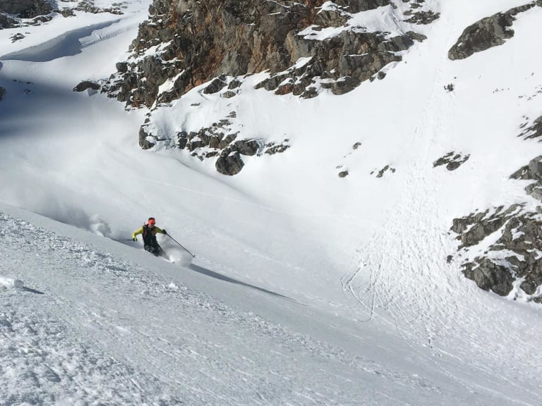 Auf Skiern fährt Bergführer Matthias Hahn einen steilen schneebedeckten Hang hinab und wirbelt dabei Schneepulver auf.