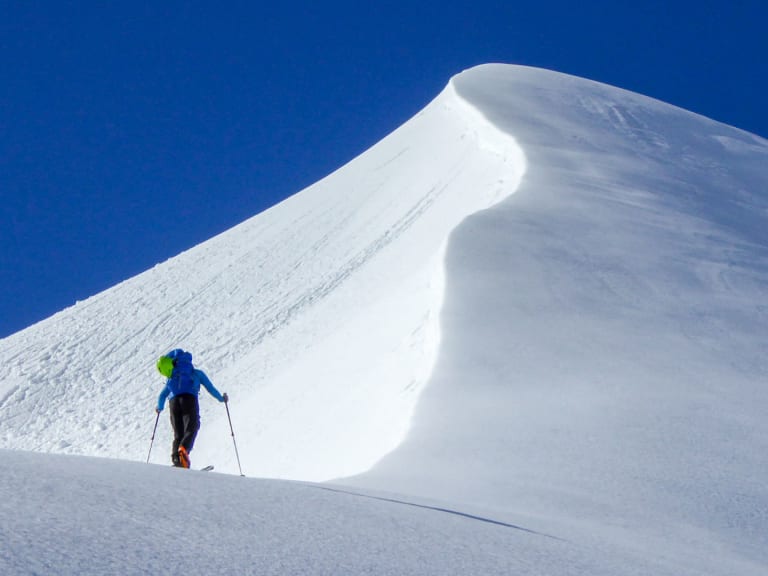 Auf Skitour steigt Bergführer Hermann Böhler einen steilen verschneiten Grat mit großer Schneewächte hinauf.