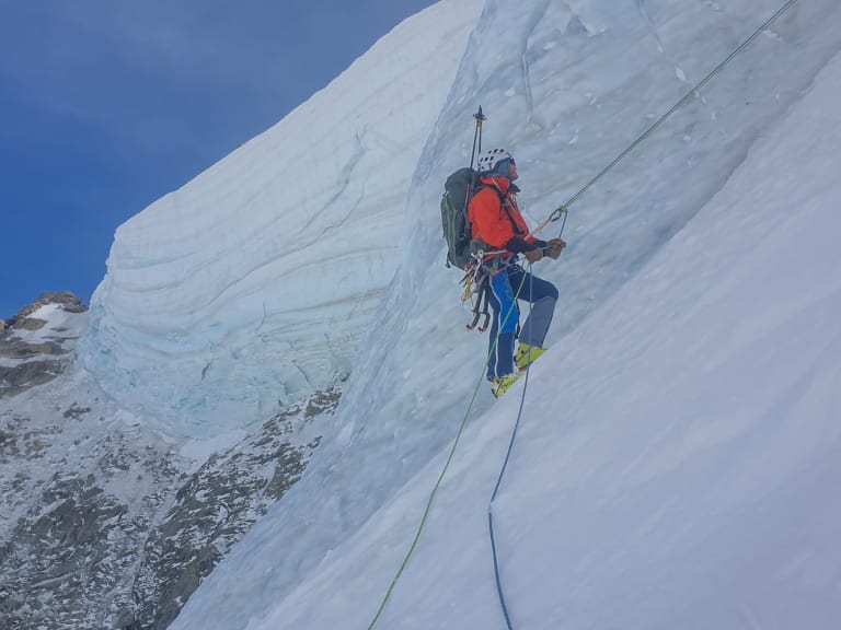 An steiler Eiswand seilt sich Bergwanderführer Christoph Knappe in roter Jacke und blauer Hose mit grünem Seil ab.