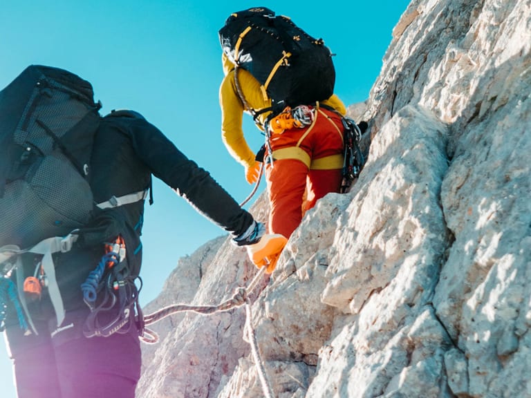Zwei angeseilte Kletterer steigen an heller Kalksteinwand nach oben - Alpinklettern mit Bergführer Enrico Trapazzo.