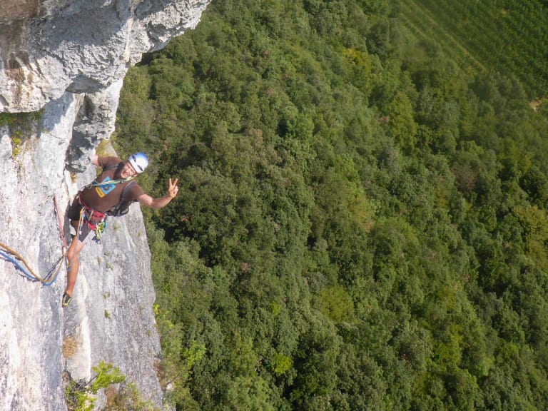 Luftaufnahme zeigt Bergführer Fabian Bendlin beim Freiklettern an steiler Kalksteinwand über bewaldetem Tal.