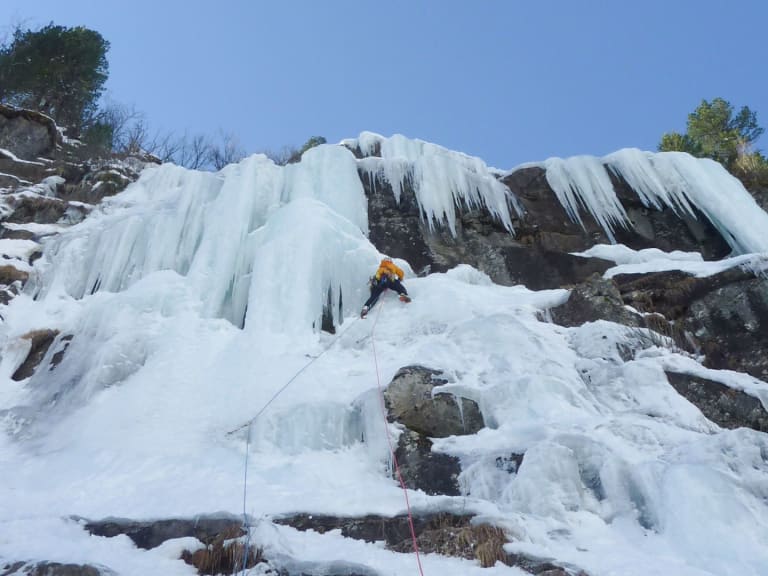Bergführer Alexander Reisenhofer klettert mit Eisgeräten an vereister Felswand mit dicken Eiszapfen.