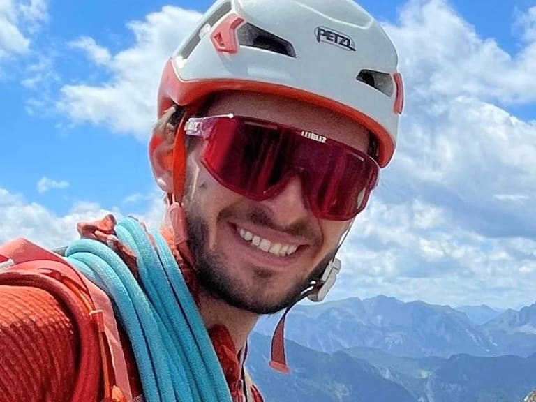 Bergführer Christoph Blumrich macht ein Selfie am Hochschwab-Gipfel mit weißem Helm und türkisem Kletterseil.