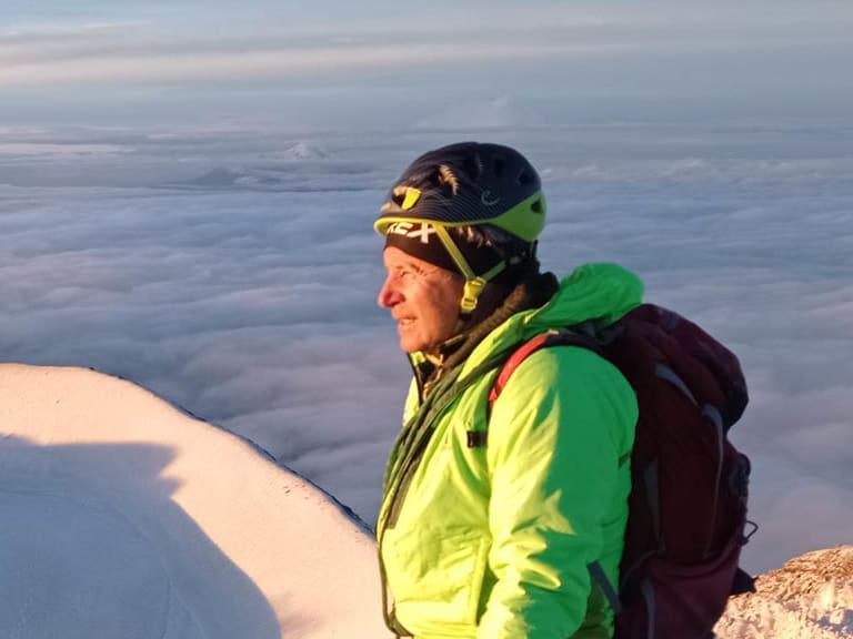 Bei der Winterwanderung steht Bergführer Jürgen Bäumler mit rotem Bergstock über der Wolkendecke im Hochgebirge.