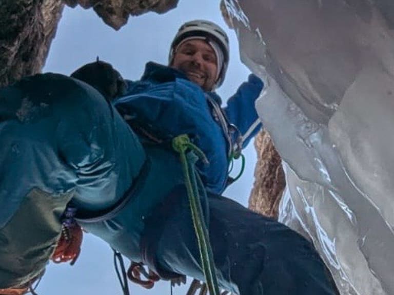 In einer steilen Eiswand klettert Bergführer Christoph Vonmetz mit Eisgeräten, Steigeisen und grünem Seil.