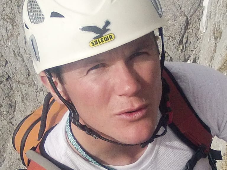 Bergführer Harald Hosner klettert an einer Felswand und zeigt seine Kletterfähigkeiten in alpinem Gelände.
