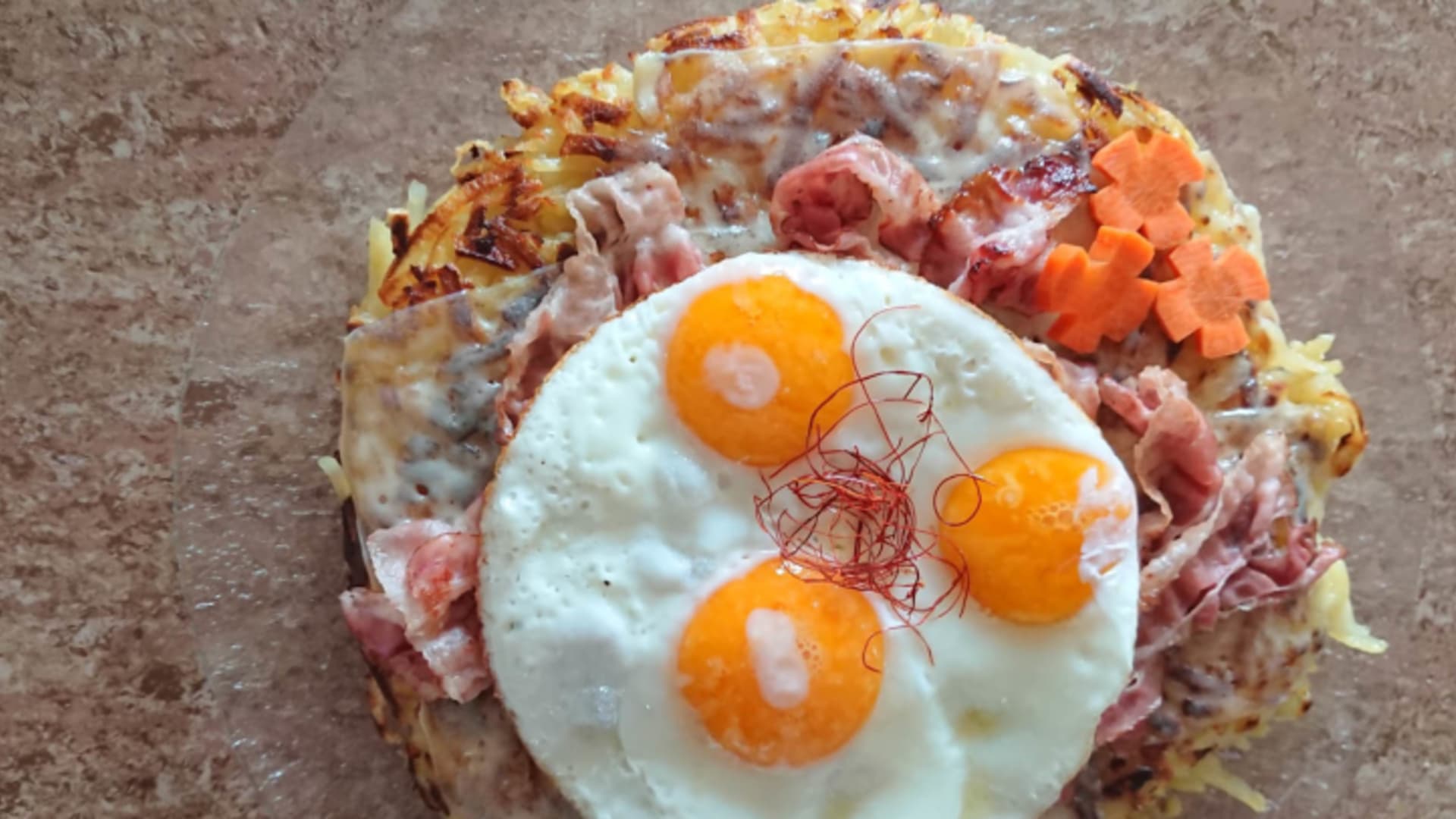 Traditionelles Rösti-Gericht mit Spiegeleiern und Speck von der Chamanna Jenatsch auf steinerner Platte.