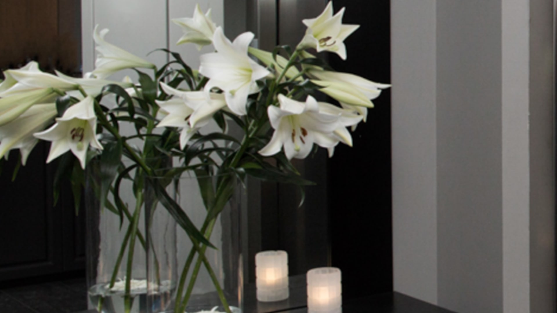 Elegante Badezimmer-Dekoration mit weißen Lilien im 22 Hill Hotel Reykjavík auf schwarzer Kommode.