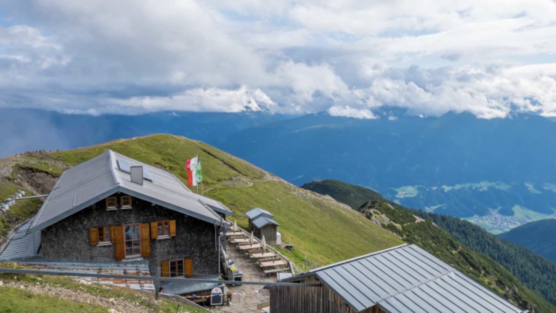Panoramablick auf die Nördlinger Hütte mit traditioneller Holzarchitektur und Terrasse auf dem Gipfelplateau.