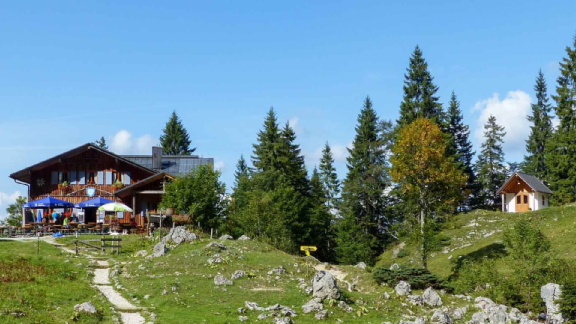 Die Tutzinger Hütte mit Holzterrasse und blau-weißer bayerischer Fahne empfängt Bergwanderer auf 1.327 m.