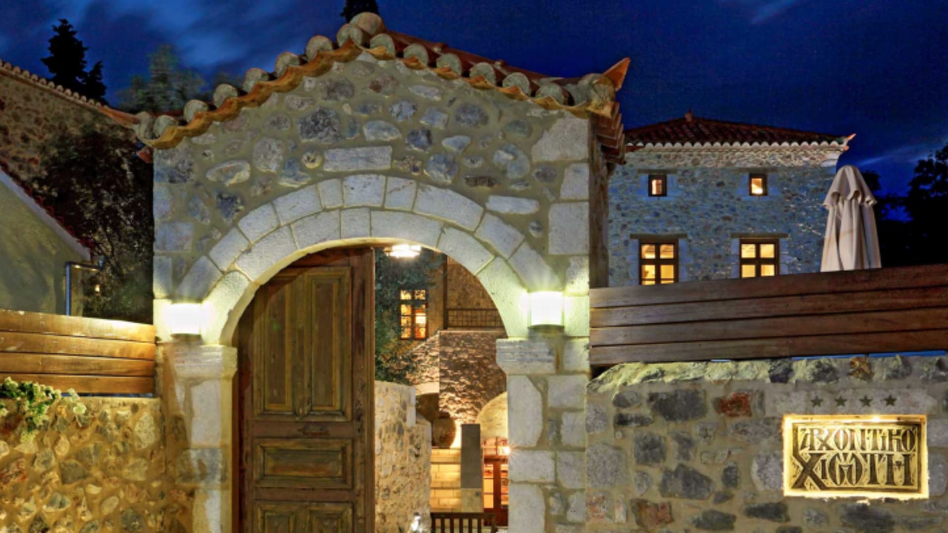 Beleuchteter Eingang des Archontiko Chioti Boutique Hotel mit traditionellem Steinportal in Leonidio.