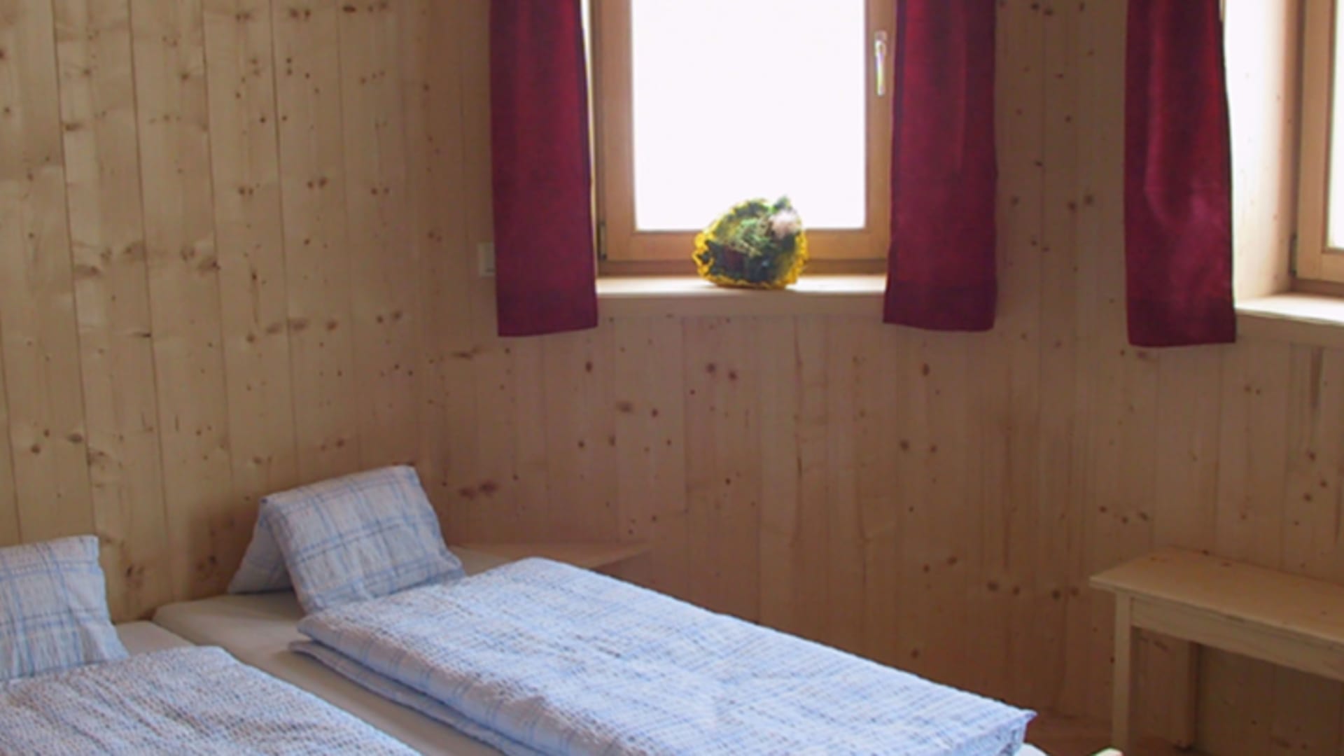 Gemütliches Schlafzimmer der Sajathütte mit zwei Einzelbetten und kompletter Zirbenholz-Ausstattung.