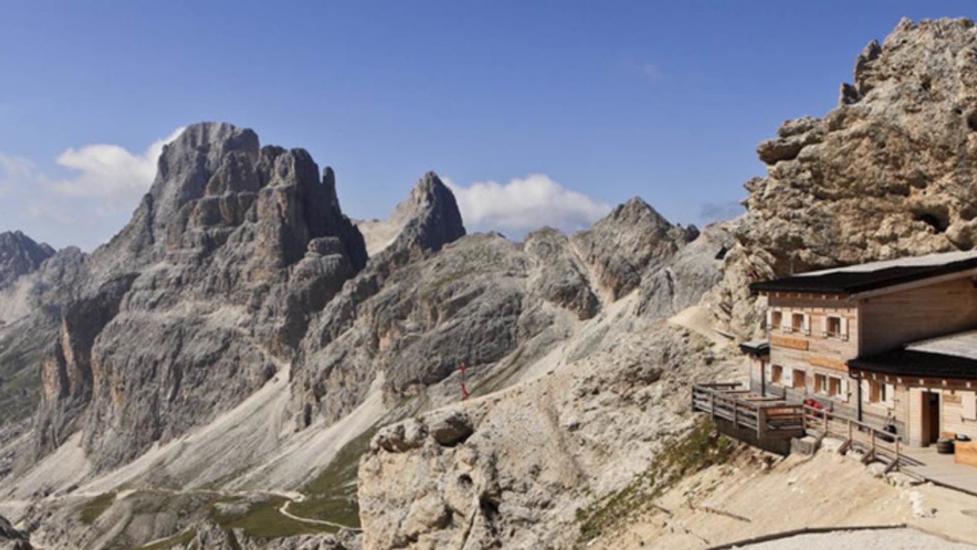 Bergwanderer auf der Terrasse der Grasleitenpasshütte vor dem Panorama der Rosengarten-Dolomiten.