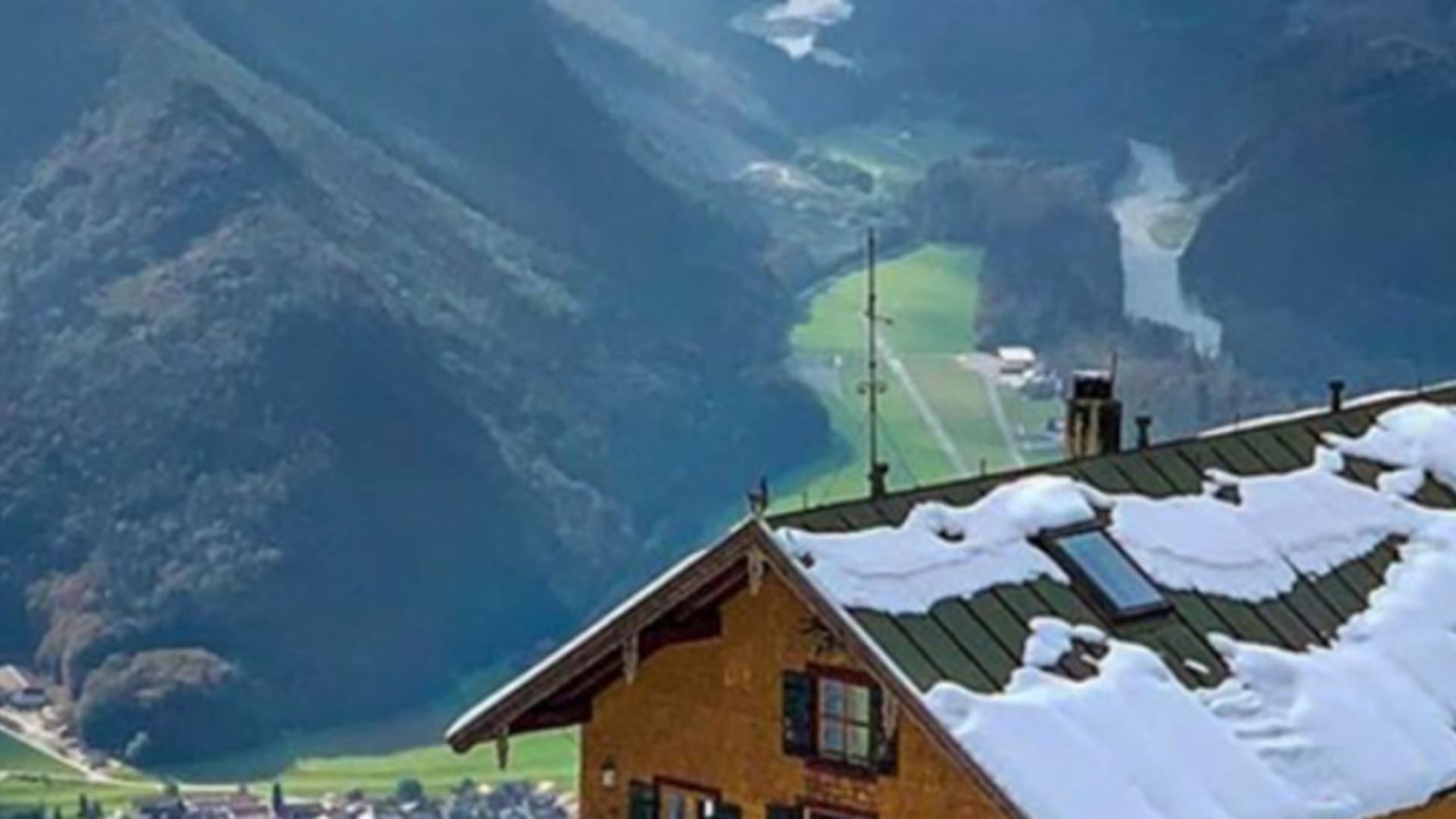 Luftaufnahme zeigt das verschneite Hochgernhaus in der Winterlandschaft der Chiemgauer Alpen mit Blick ins Tal.
