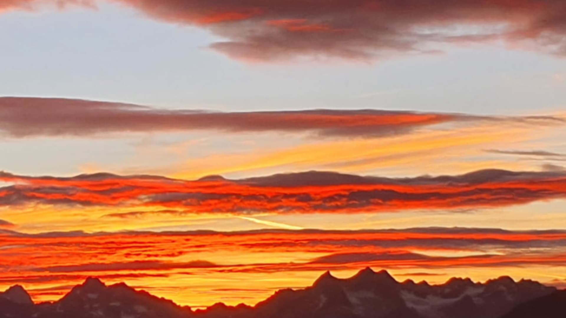 Bergpanorama bei Dämmerung von der Siegerlandhütte mit orange-gelbem Himmel über den Stubaier Alpen.