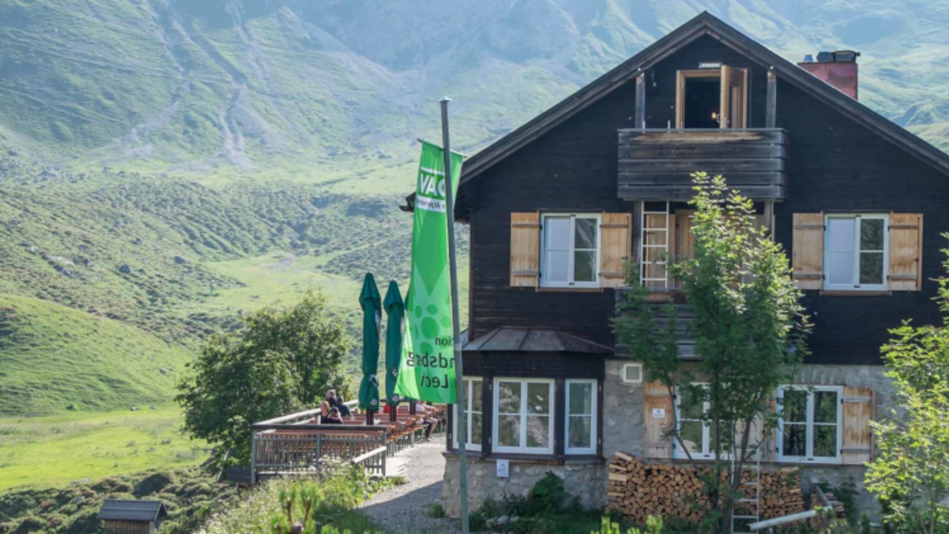 Die Landsberger Hütte zeigt zweistöckige Holzbauweise mit Balkon und Terrasse im Bergtal.