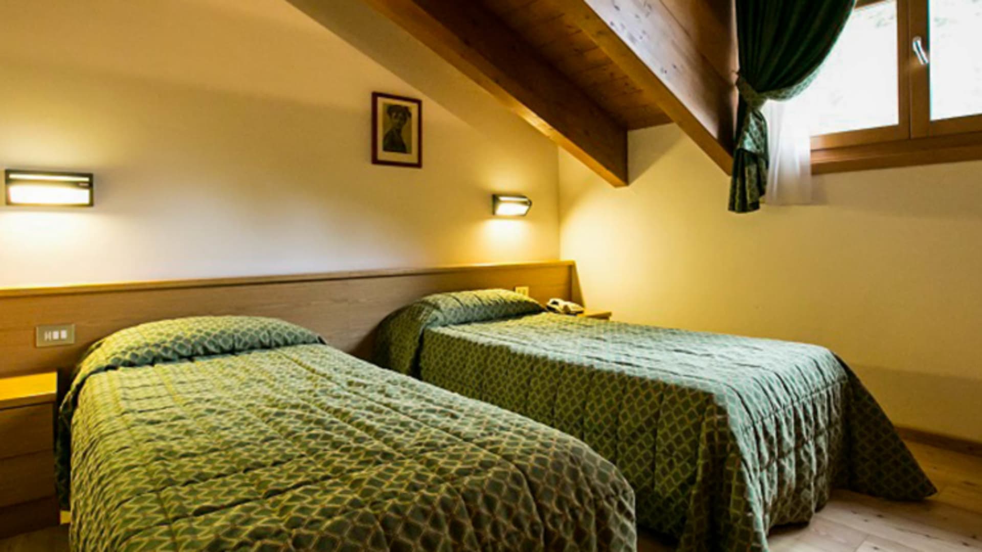 Gemütliches Doppelzimmer mit zwei Einzelbetten unter Dachschräge im Garni Lago Nembia.