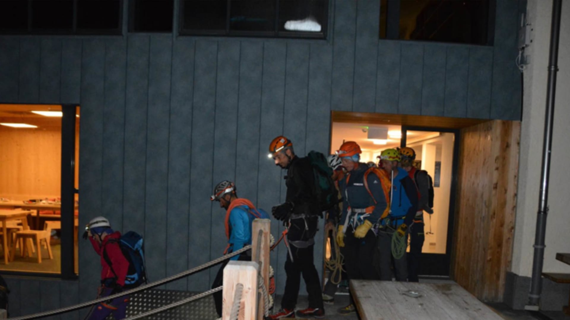 Bergsteiger mit Kletterausrüstung bereiten sich auf der überdachten Terrasse der Hörnlihütte vor.