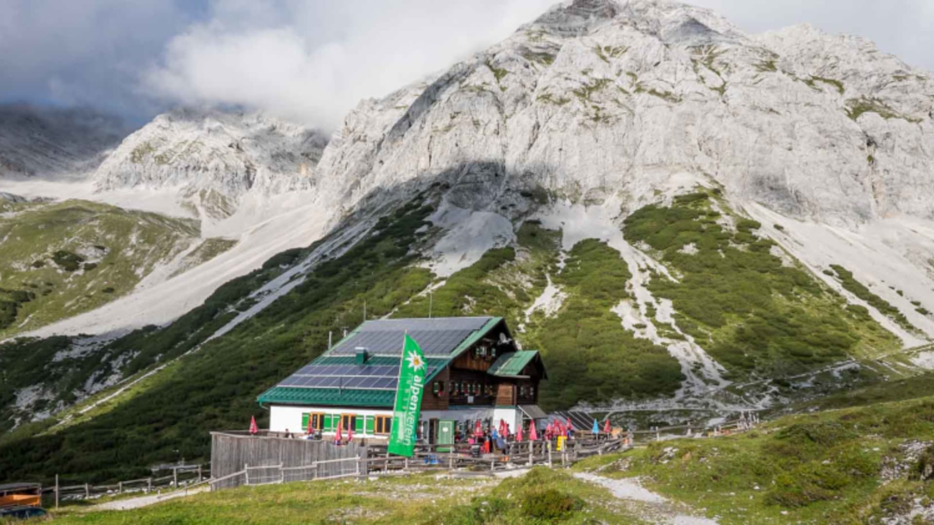 Pfeishütte mit roten Sonnenschirmen auf der Terrasse unterhalb der Karwendel Felswände.