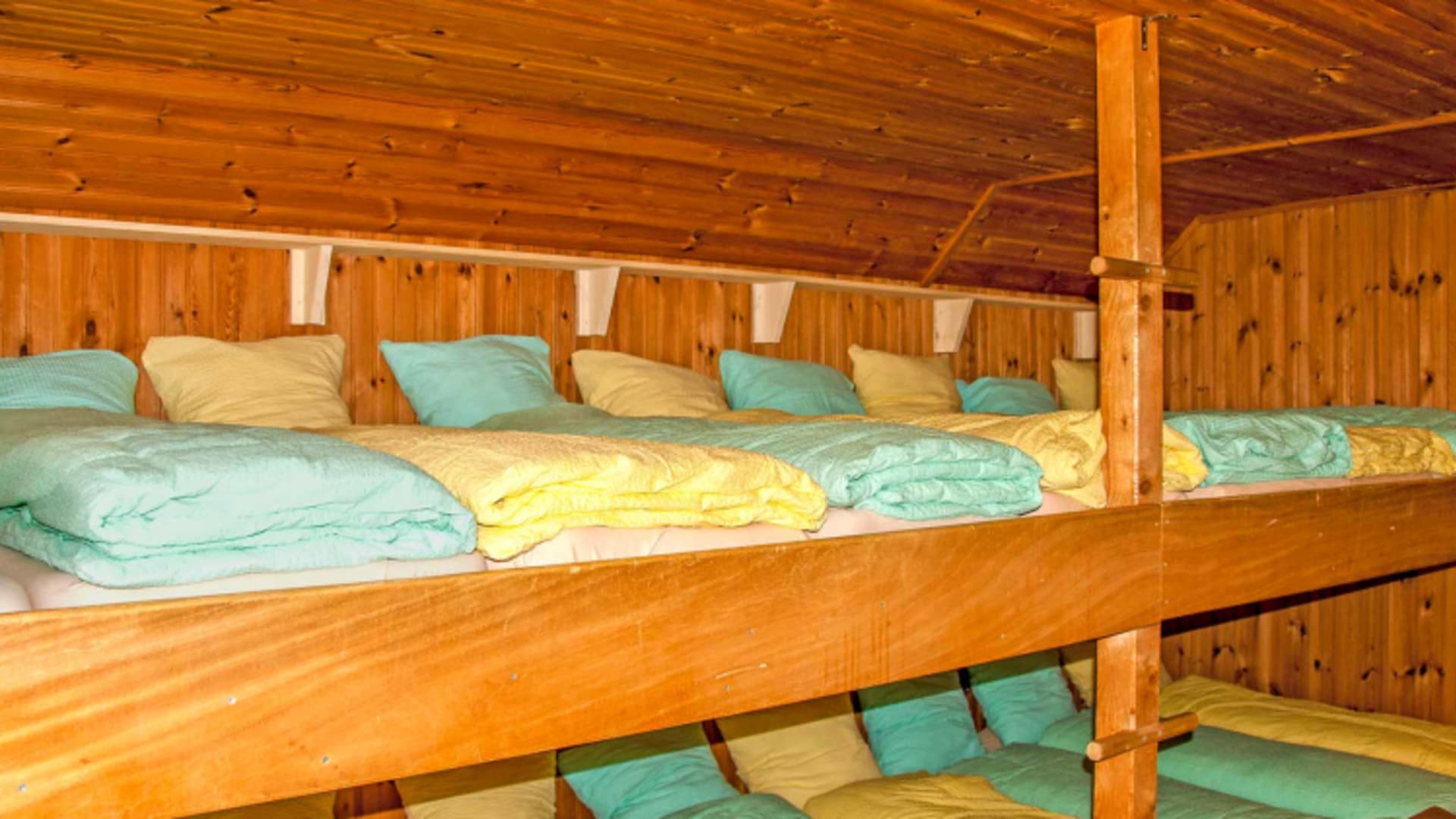 Zweistöckige Holzpritschen im Matratzenlager der Gafadurahütte mit Massivholzkonstruktion.
