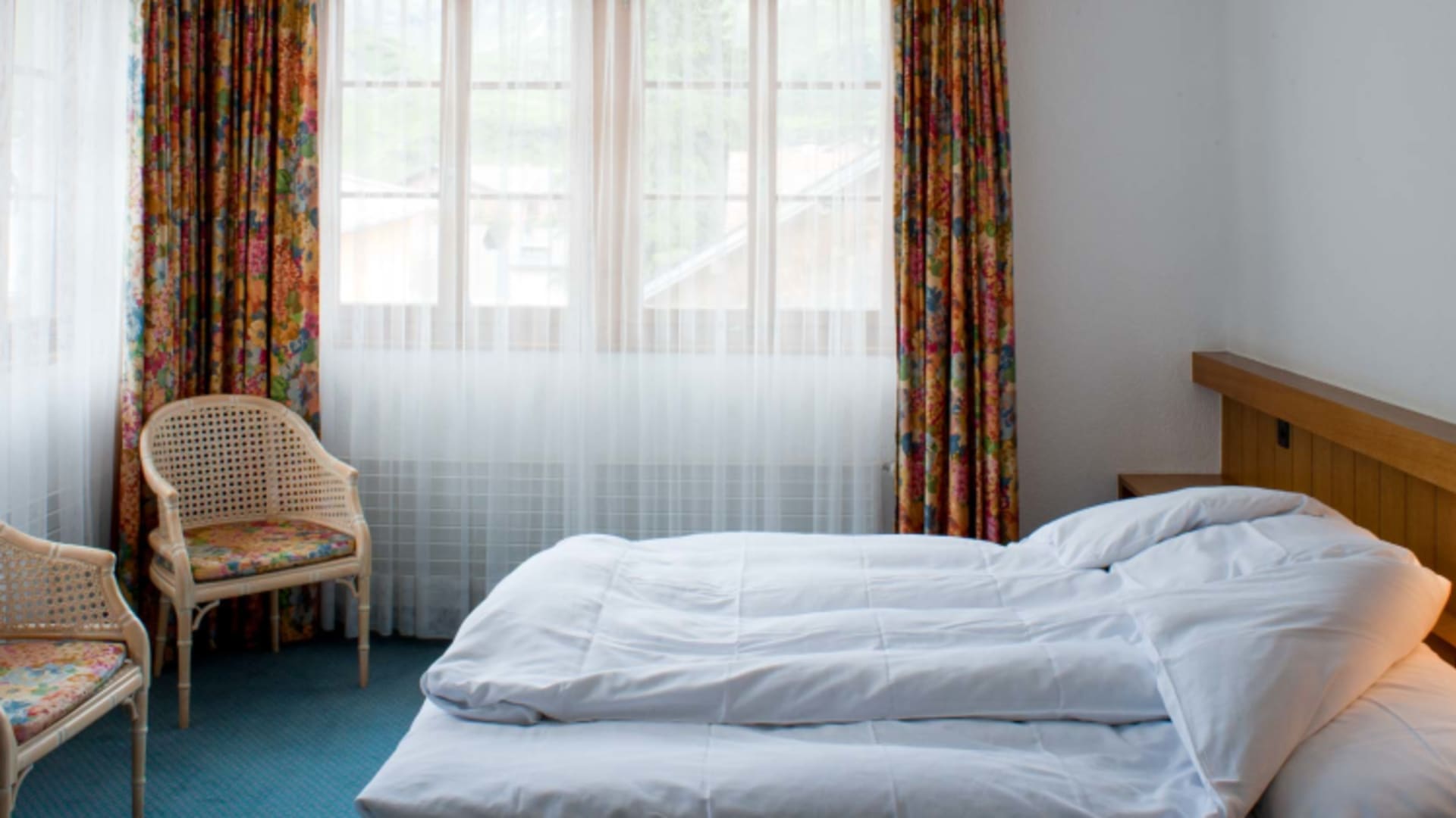 Gemütliches Doppelzimmer im Hotel Post Bivio mit Arvenholzmöbeln und bunten Vorhängen auf 1.770 m Höhe.