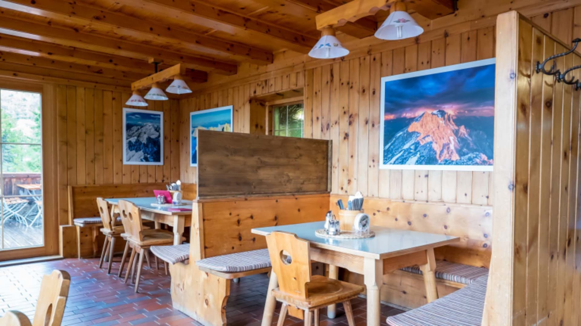 Gemütliche Gaststube im Hallerangerhaus mit Zirbenholzverkleidung, Eckbank und Bergfotografien an den Wänden.