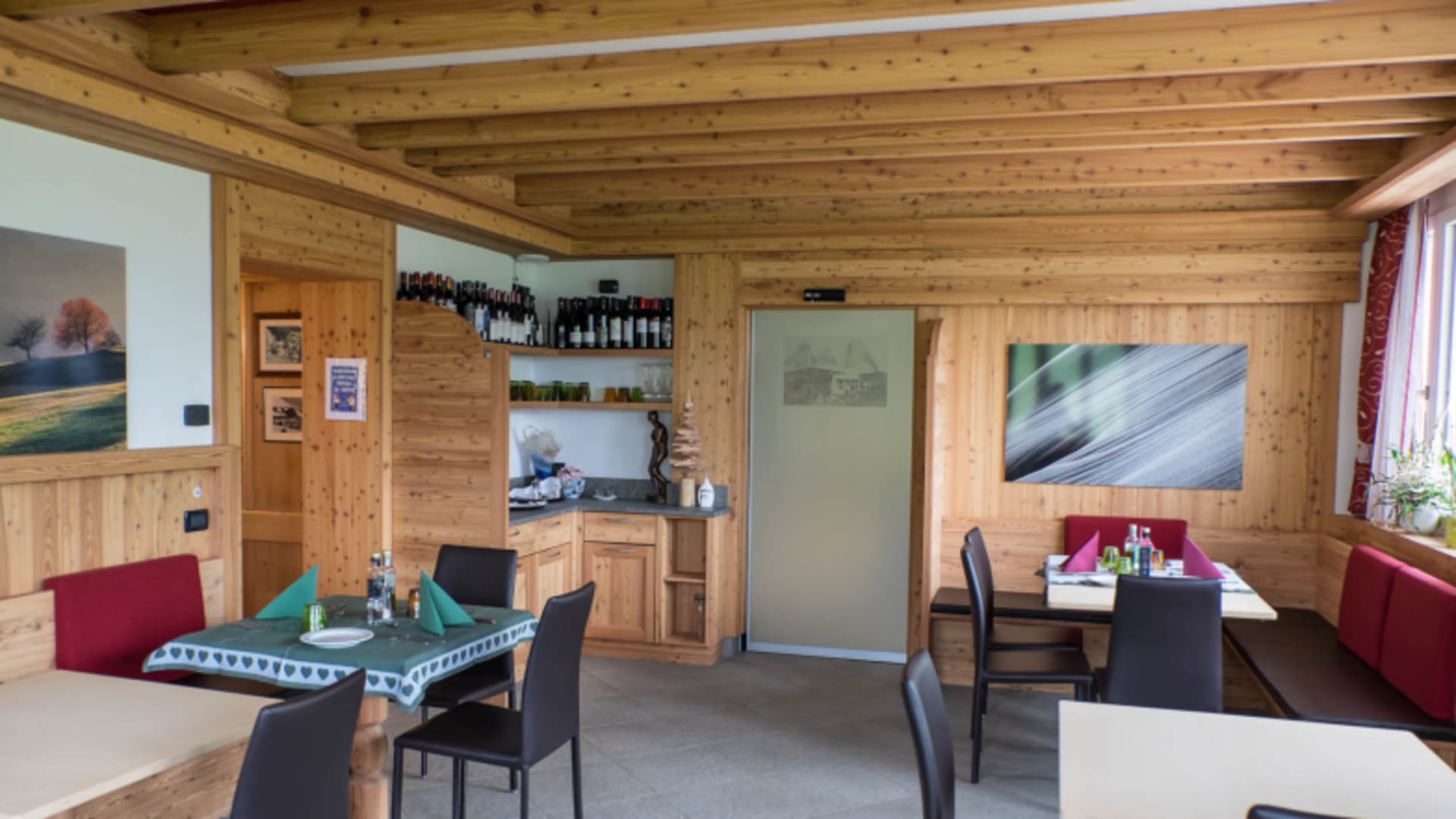 Traditioneller Gastraum im Rifugio Carlo Valentini mit Sichtbalkendecke und Holzverkleidung.