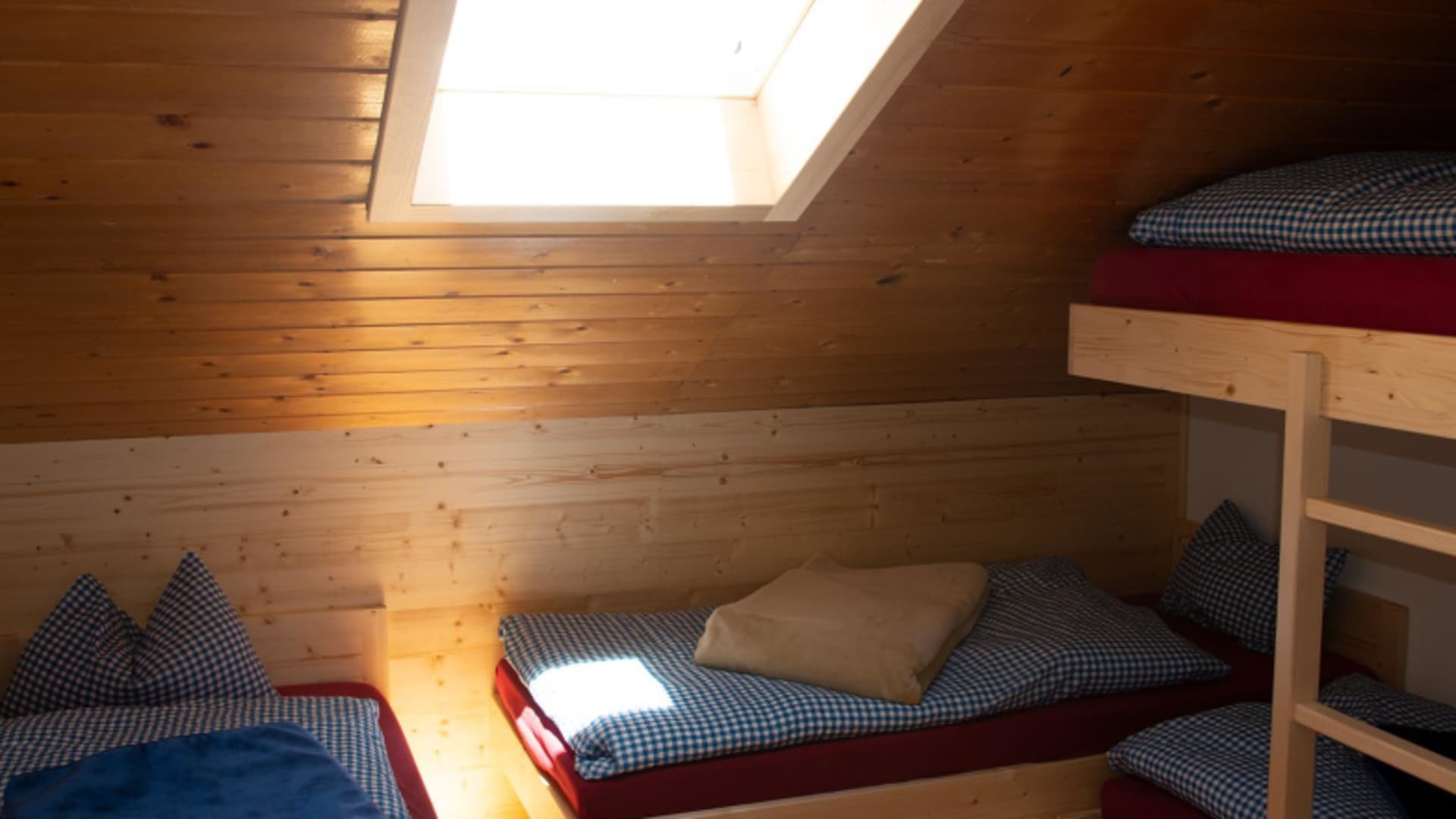 Schlafraum der Blaueishütte mit Etagenbett und Holzverkleidung unter dem Dach.