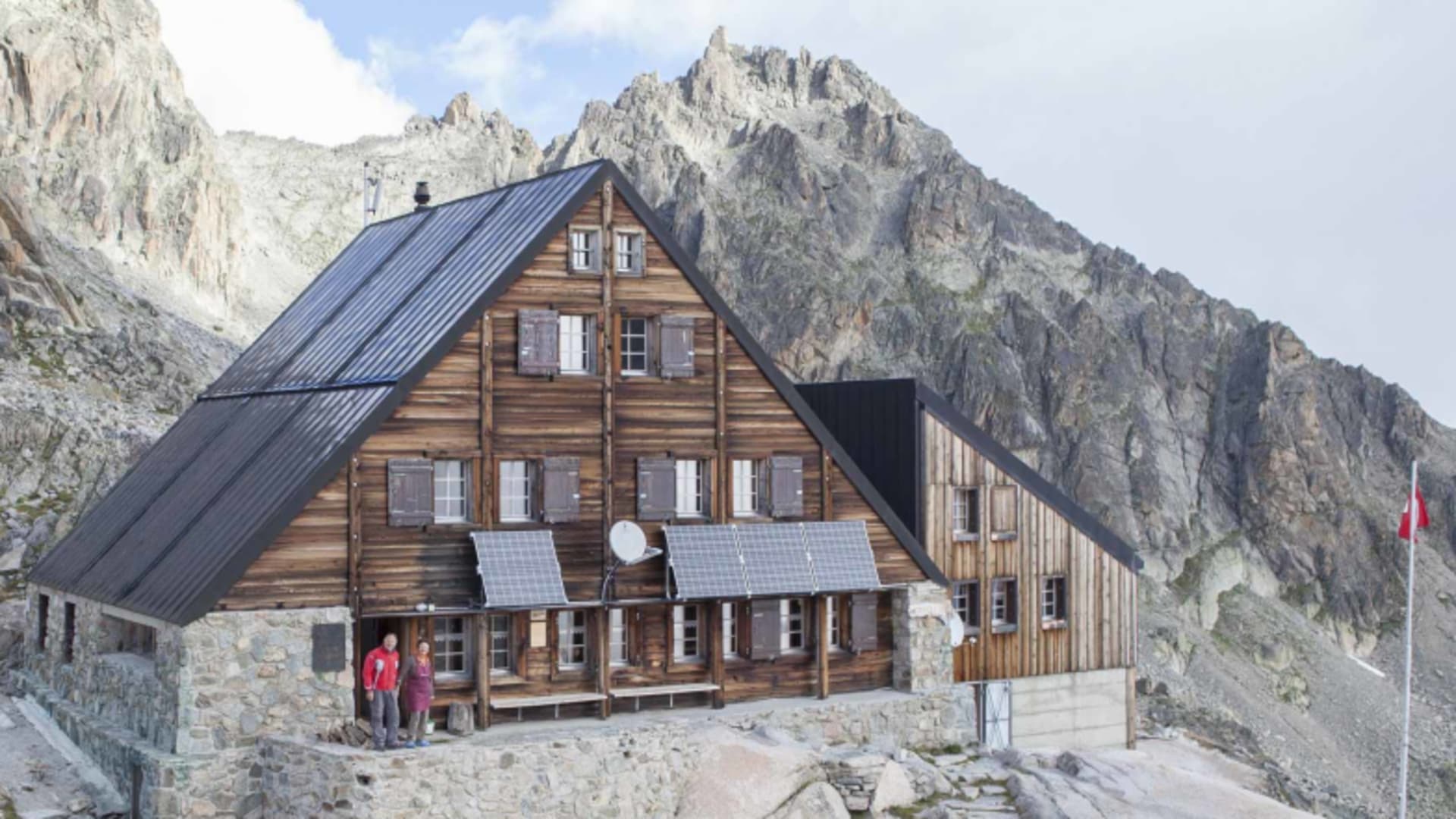 Die Cabane d'Orny zeigt traditionelle Schweizer Holzbauweise mit modernem Anbau und Solarpanels auf dem Dach.