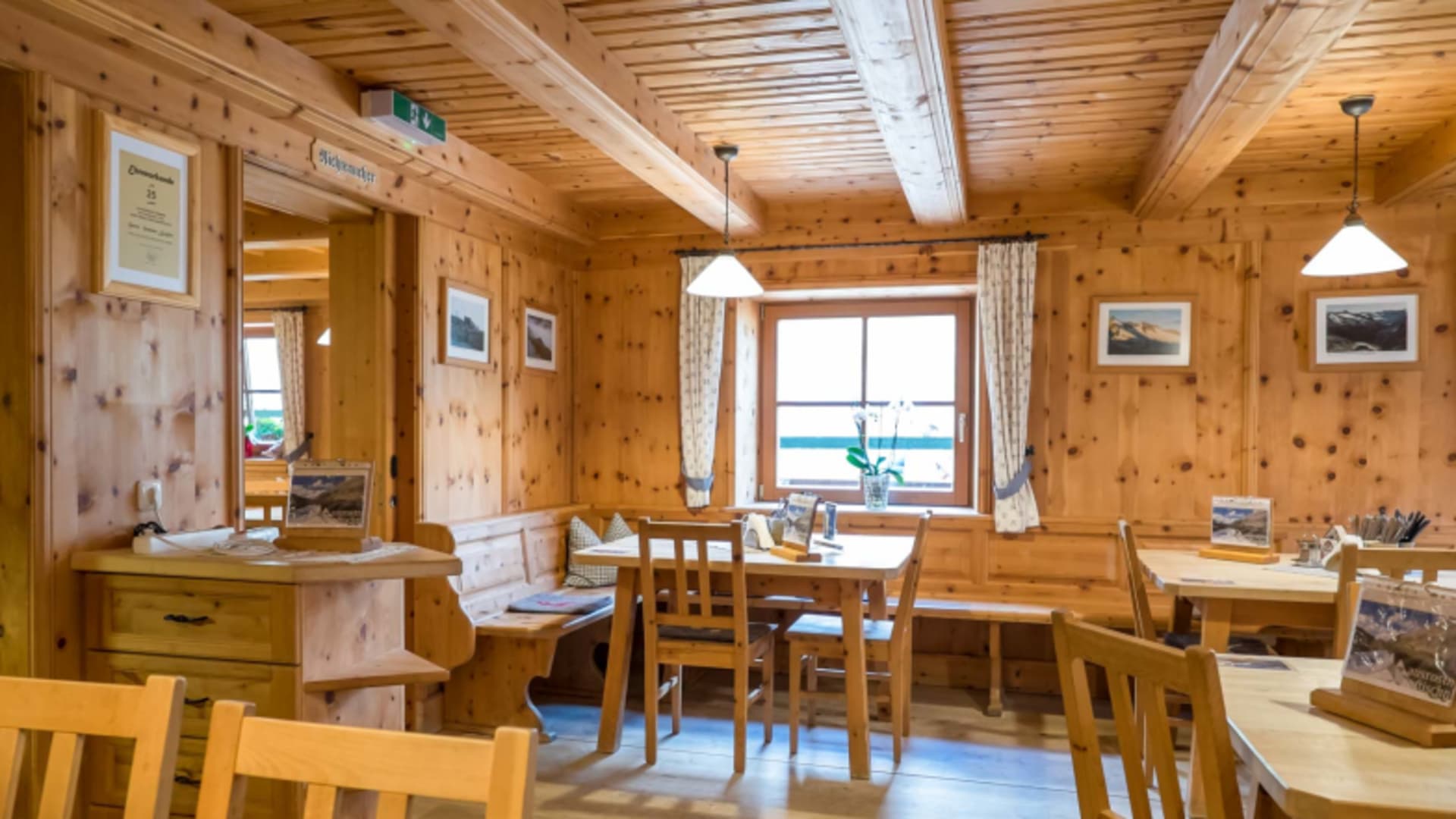 Gastraum der Zittauer Hütte mit traditioneller Zirbenholz-Ausstattung und gemütlichen Holztischen.