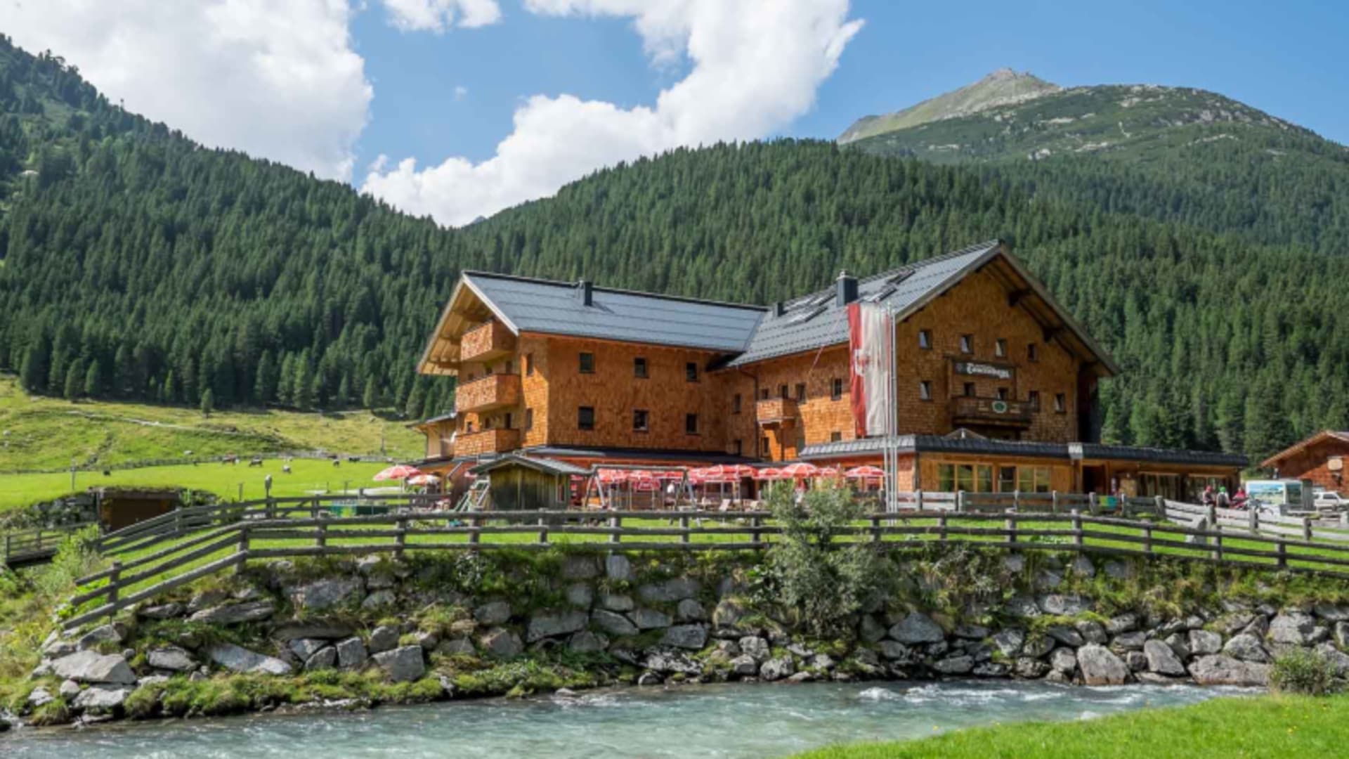 Das Krimmler Tauernhaus steht direkt am türkisblauen Gebirgsbach mit roter Sonnenterrasse.