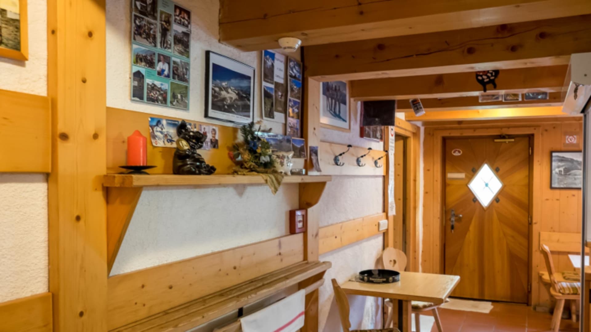 Rustikaler Aufenthaltsraum der Birnlückenhütte mit Holzbank und Bergfotografien an den Wänden.