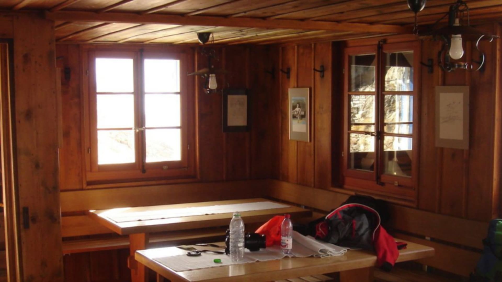 Gastraum der Chelenalphütte mit Holztisch, Sitzbank und traditioneller Holzverkleidung an den Wänden.