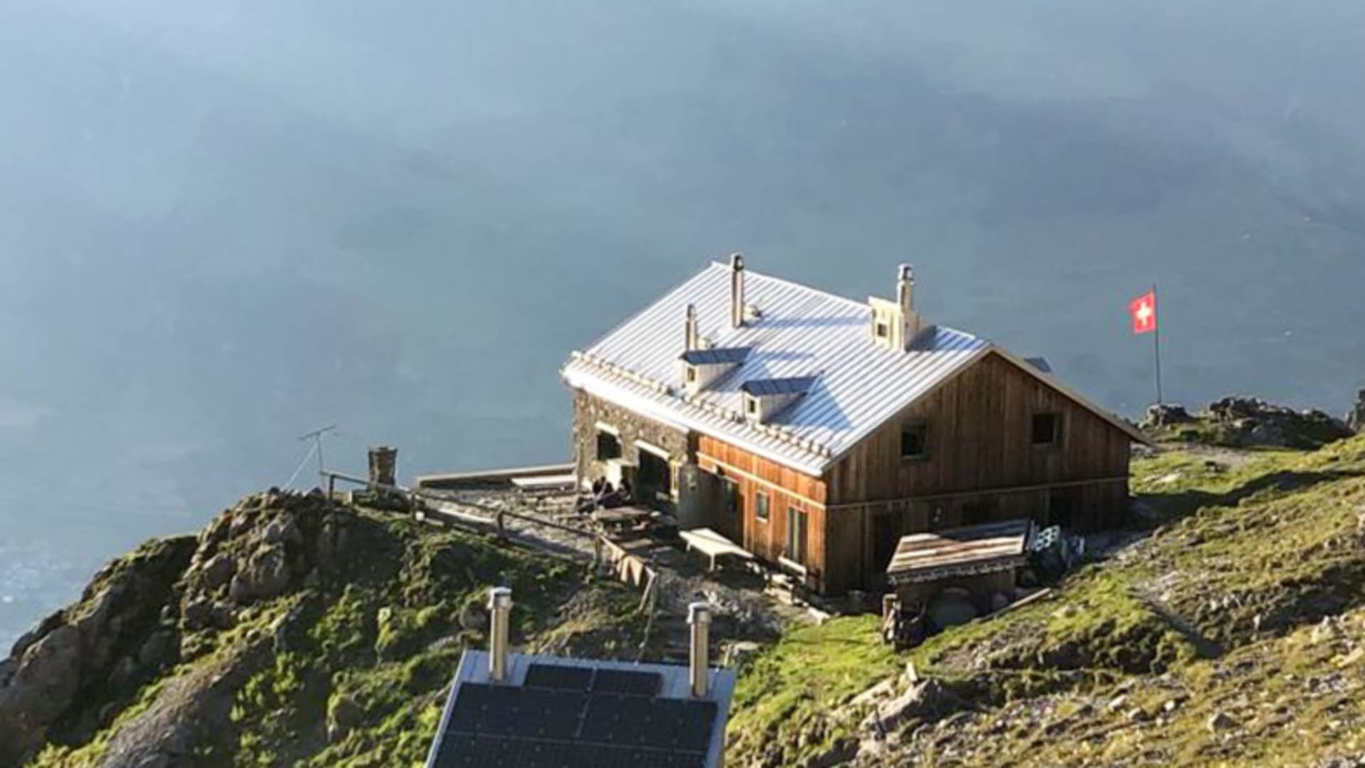 Die Chamanna Lischana steht auf einem schmalen Felsgrat in nebelverhangener Berglandschaft Graubündens.