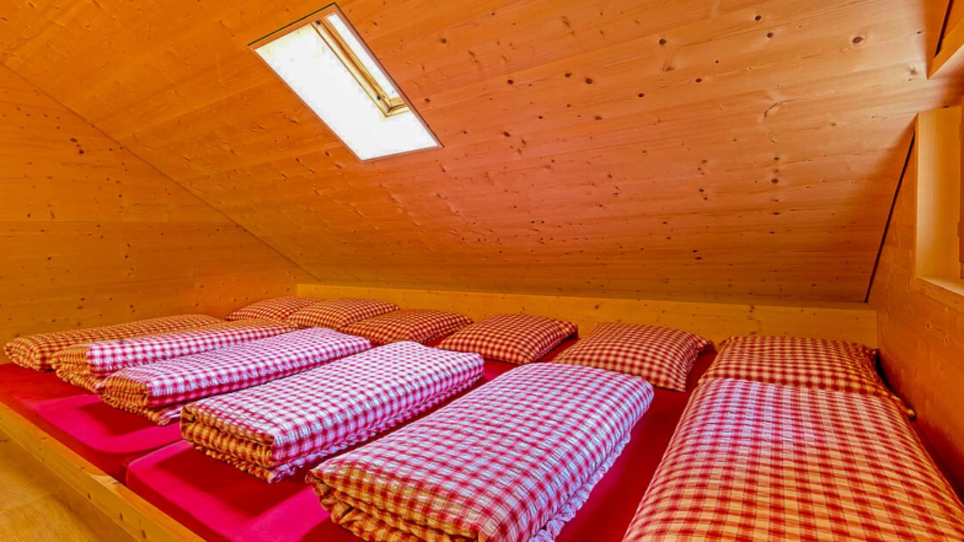 Matratzenlager mit fünf Schlafplätzen und karierter Bettwäsche im Berggasthaus Bollenwees in den Appenzeller Alpen.