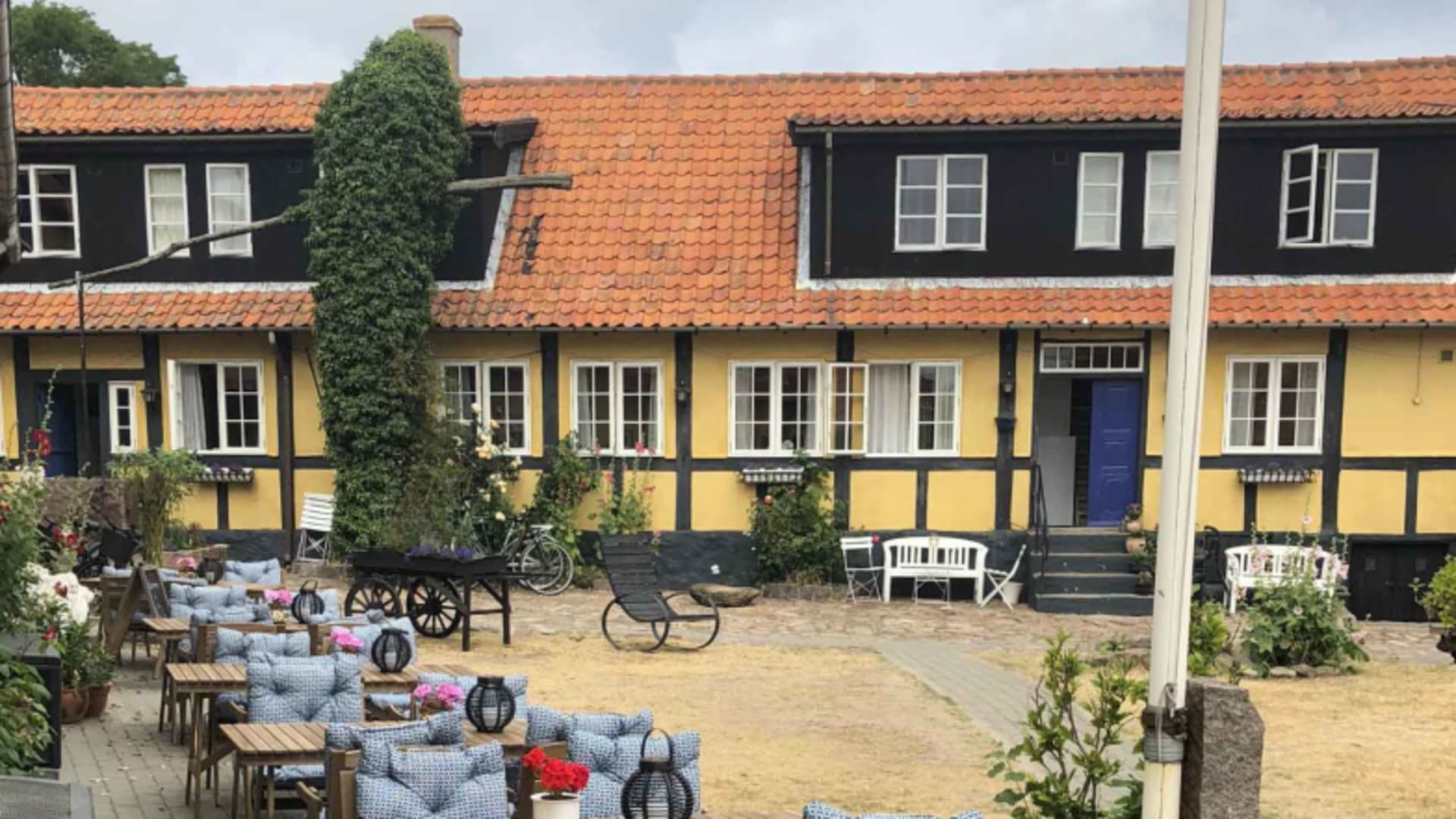Fachwerkhaus der Pension Slaegtsgaarden mit gelben Wänden und gepflastertem Innenhof.