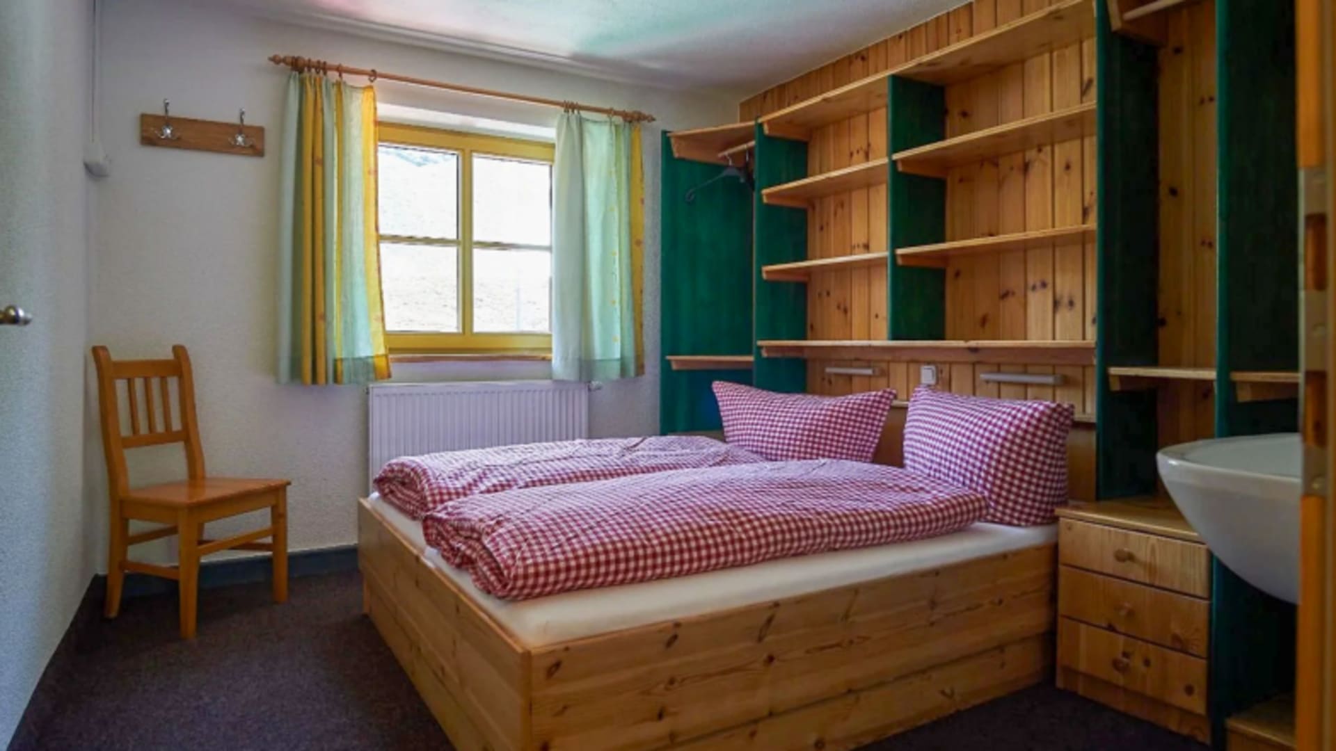 Doppelzimmer im Madlenerhaus mit Massivholzbett und grün-gelber Schrankwand in alpinem Stil.