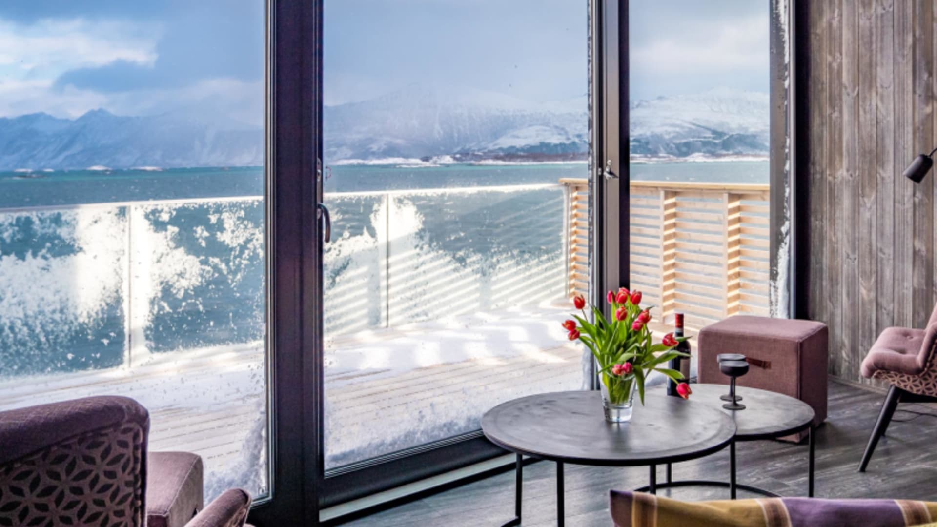 Lounge-Bereich des Aurora Rooms im Hamn i Senja mit violetten Sesseln und Fjordblick.