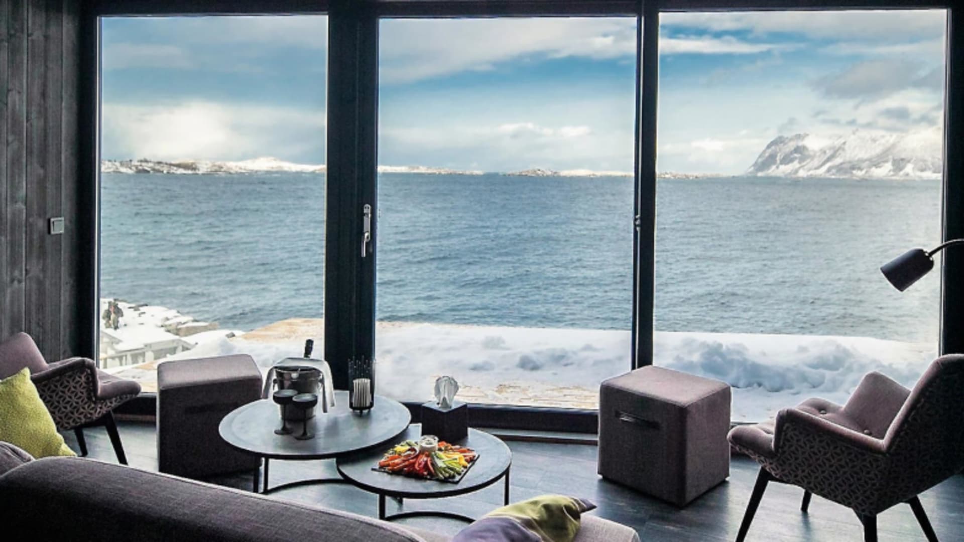 Moderner Lounge-Bereich im Aurora Room des Hamn i Senja mit Panoramafenster zum Fjord.