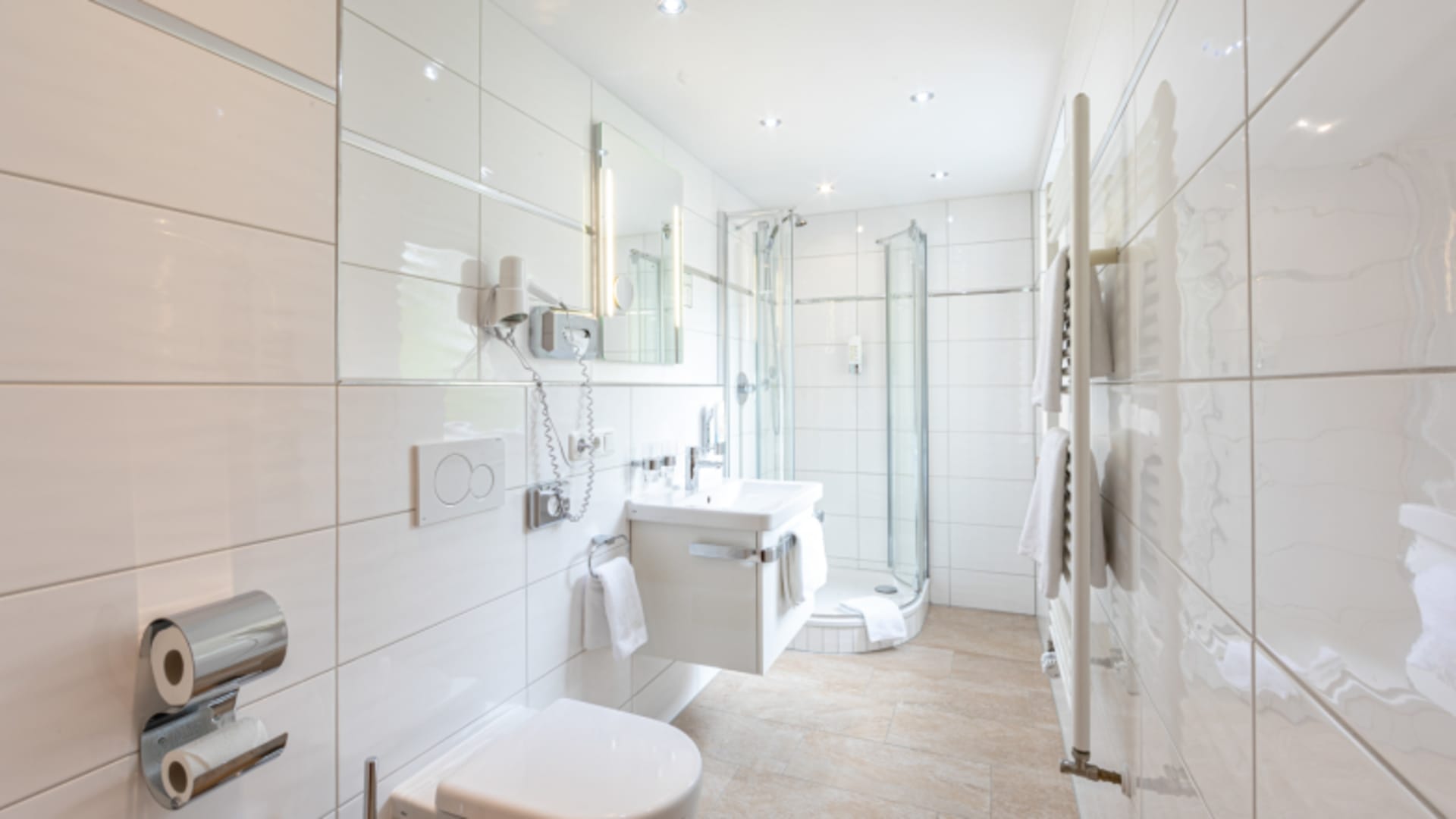 Helles Hotelbadezimmer mit Glasdusche und modernen Fliesen im Hotel AlpinaRos Demming.