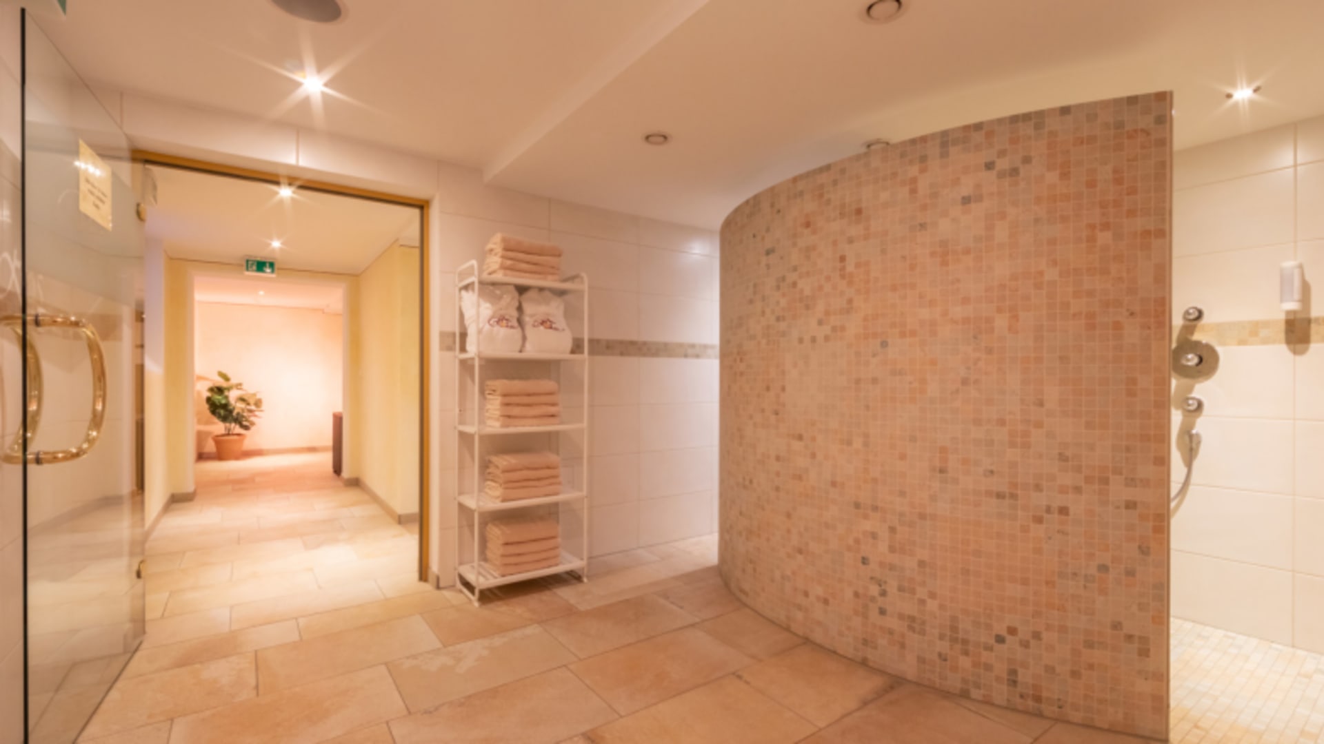 Runder Mosaikpool im Spa-Bereich mit Duschen und Handtüchern im Hotel AlpinaRos Demming.