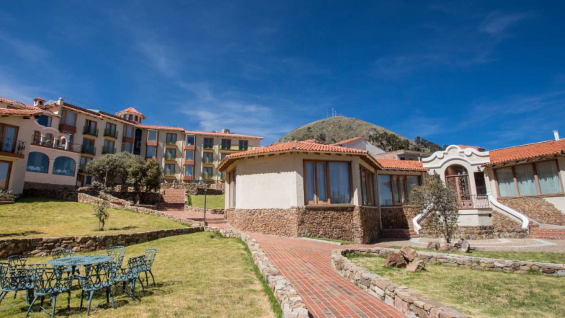 Gartenanlage des Hotel Rosario Lago Titicaca mit mediterraner Architektur und terrassierten Grünflächen am Titicacasee.