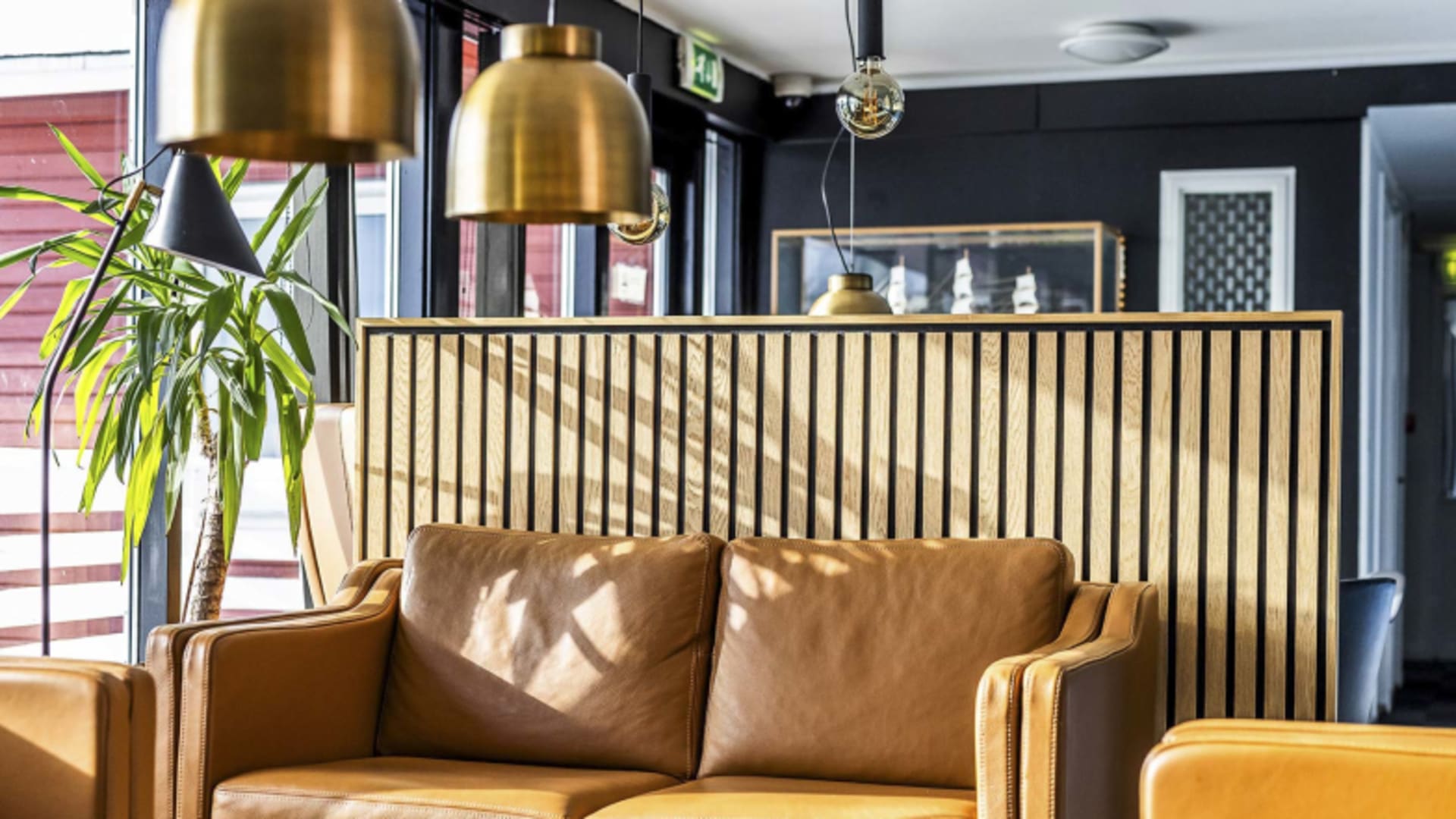Moderne Lobby im Hotel Søma Nuuk mit hellbraunen Ledersofas und goldenen Pendelleuchten.