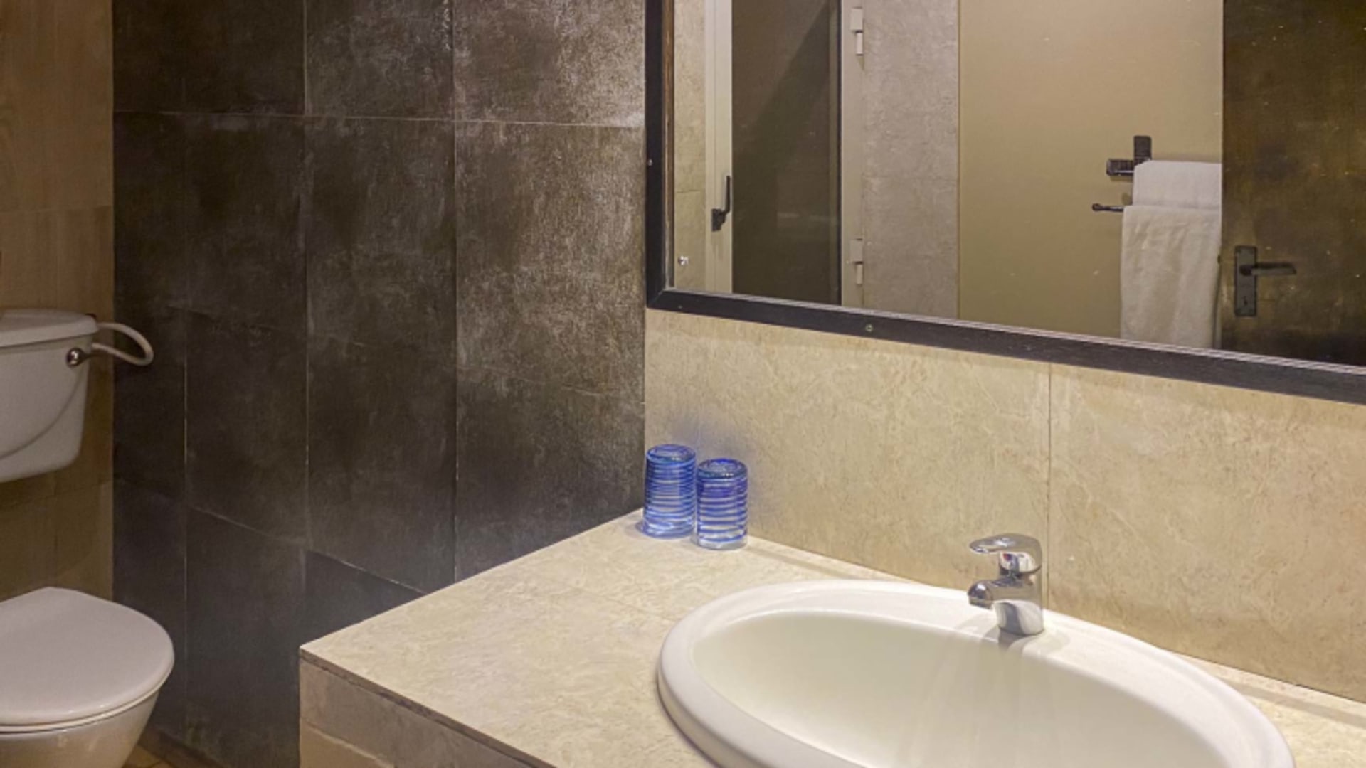 Badezimmer mit ovalem Einbauwaschbecken und Natursteinfliesen in der AMEG Lodge.