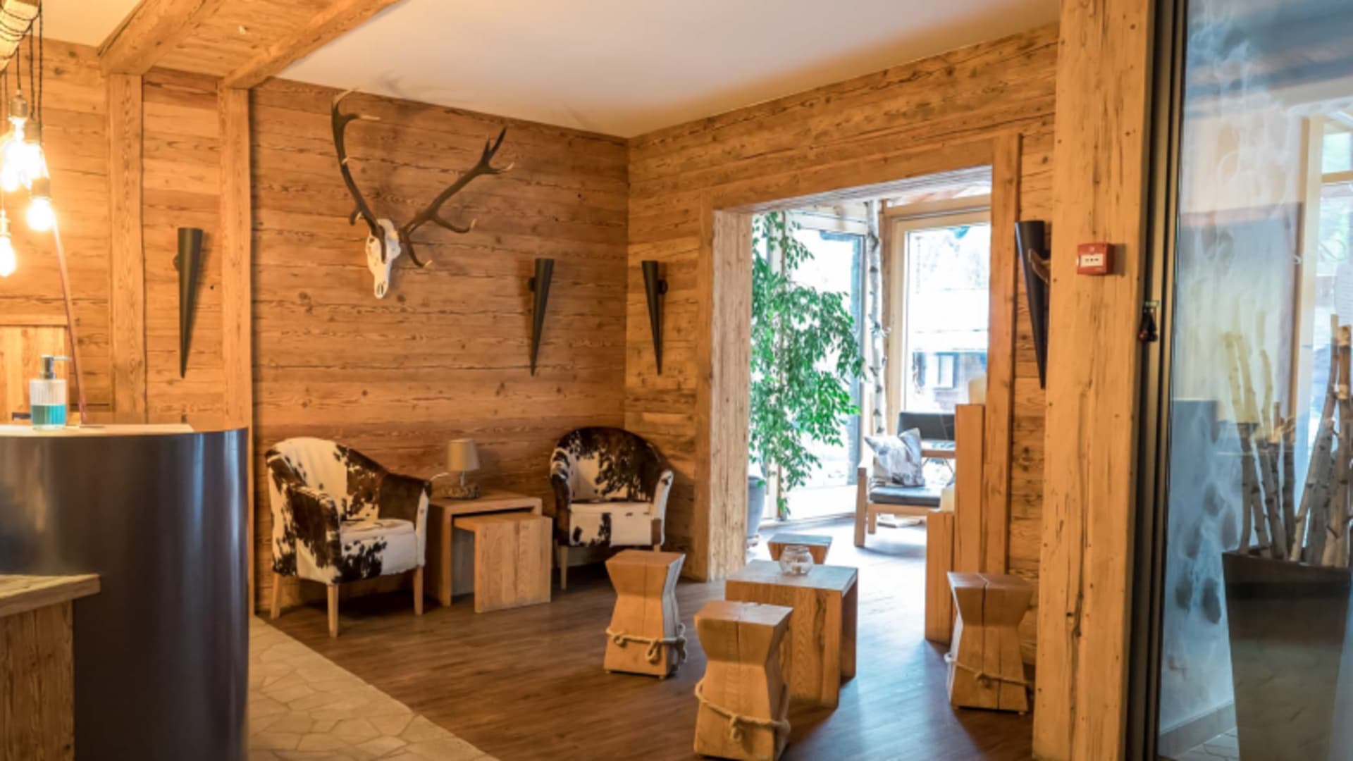 Rezeptionsbereich im Hotel Bergfreund mit vollständiger Holzvertäfelung, Hirschgeweih und alpiner Einrichtung.